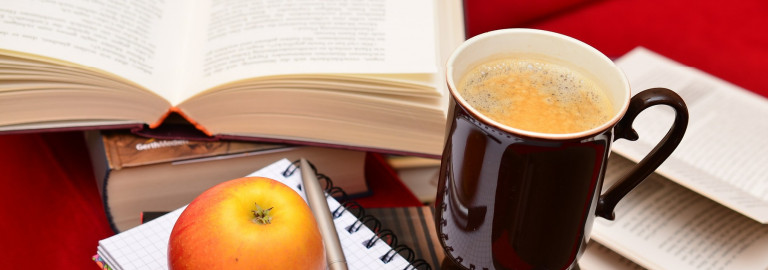 Bücher, Kaffeetasse und Apfel