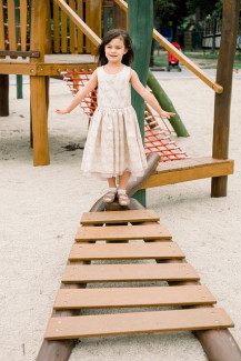 Mädchen am Spielplatz auf einer Holzbrücke